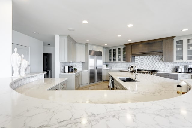 kitchen featuring glass insert cabinets, stainless steel appliances, a sink, and decorative backsplash