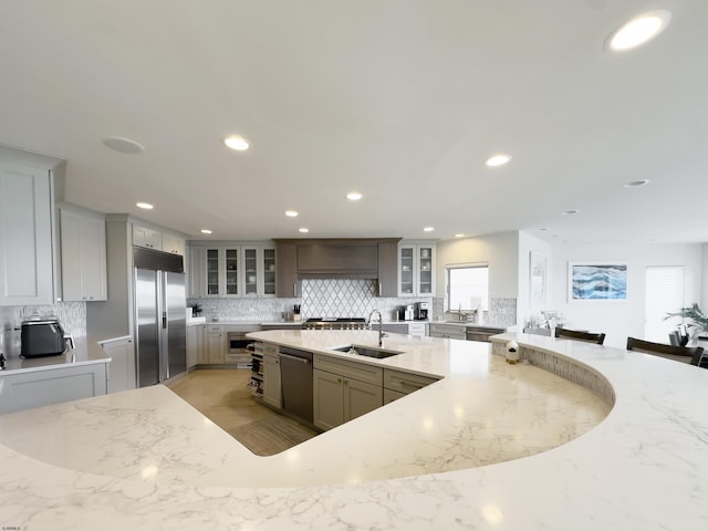 kitchen featuring stainless steel appliances, tasteful backsplash, a sink, and glass insert cabinets