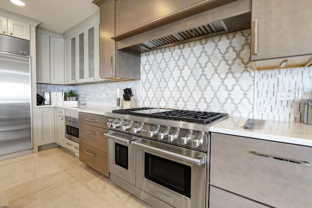 kitchen featuring custom exhaust hood, high quality appliances, glass insert cabinets, and light countertops