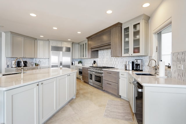 kitchen with premium appliances, white cabinets, glass insert cabinets, and a sink