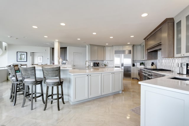 kitchen featuring light countertops, a center island with sink, a breakfast bar area, and high quality appliances