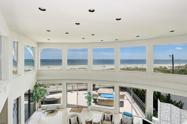 sunroom with a water view and a view of the beach