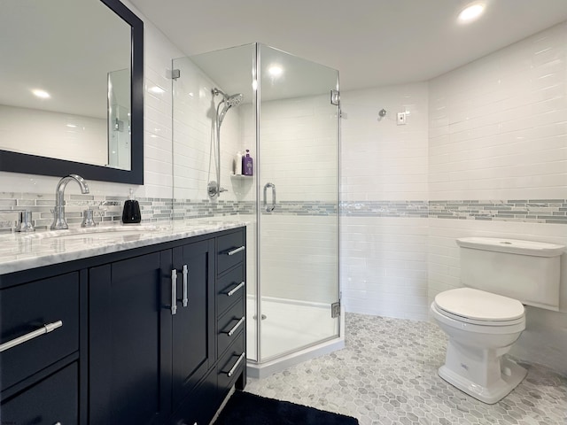 bathroom with toilet, a stall shower, vanity, and tile walls