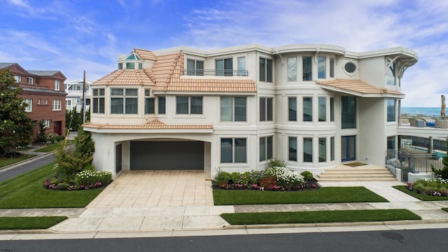 view of front of home with a garage, stucco siding, decorative driveway, and a tiled roof