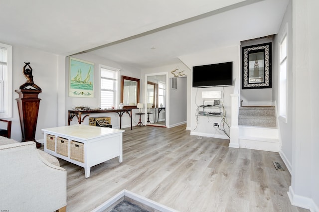 living room with light wood-style floors, visible vents, stairway, and baseboards