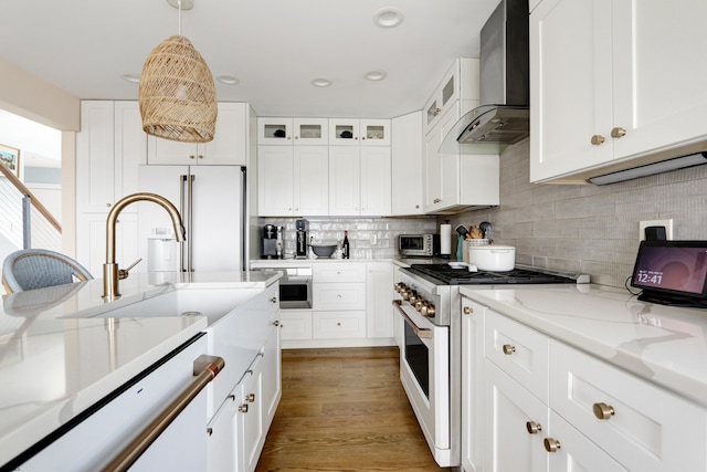 kitchen featuring high end appliances, white cabinets, glass insert cabinets, and wall chimney exhaust hood