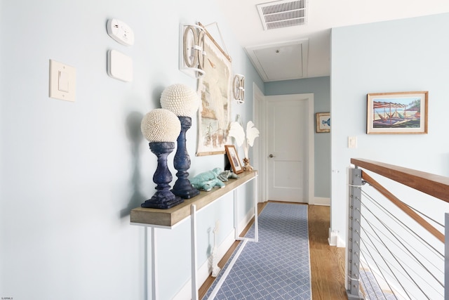 corridor featuring light wood finished floors, attic access, visible vents, and baseboards