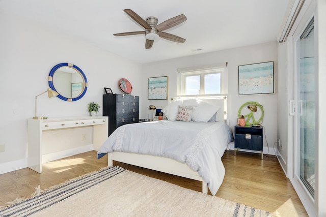 bedroom featuring light wood finished floors, visible vents, baseboards, and a ceiling fan