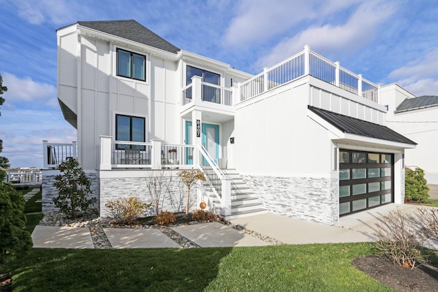 view of front of property featuring metal roof, a balcony, concrete driveway, stairway, and a standing seam roof