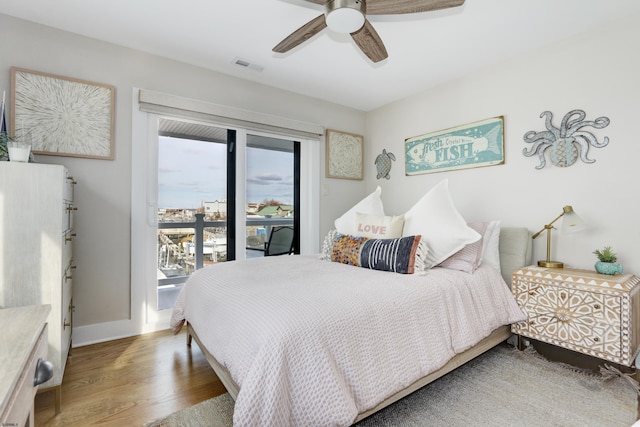 bedroom with access to exterior, visible vents, ceiling fan, wood finished floors, and baseboards