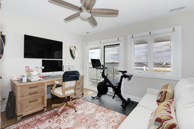 home office featuring a ceiling fan, visible vents, baseboards, and wood finished floors