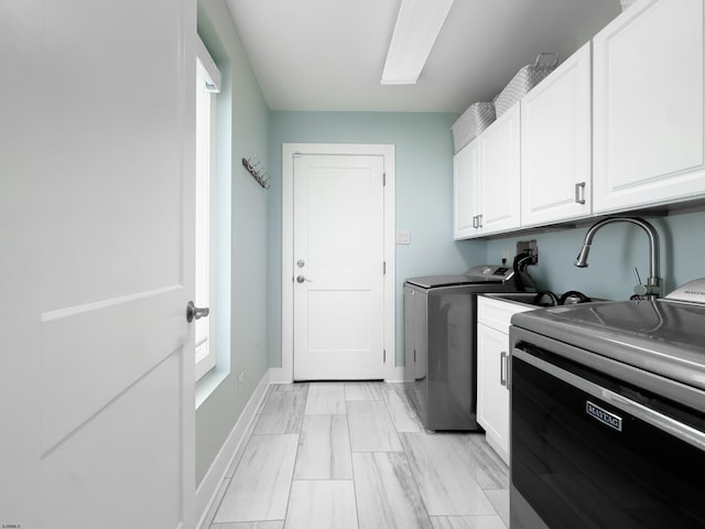 clothes washing area featuring baseboards, cabinet space, and washing machine and clothes dryer