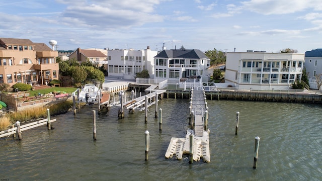 view of dock with a water view, boat lift, and a residential view