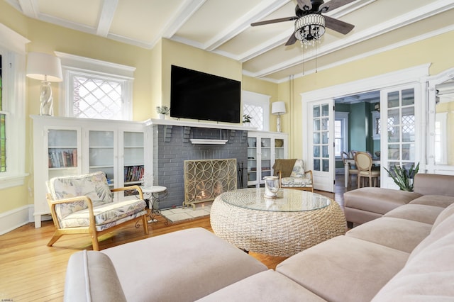 living area featuring a fireplace, wood finished floors, beam ceiling, and a healthy amount of sunlight