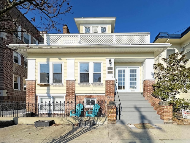 view of front of property featuring french doors, brick siding, and a fenced front yard