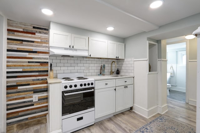 kitchen with white electric stove, light countertops, white cabinetry, a sink, and under cabinet range hood