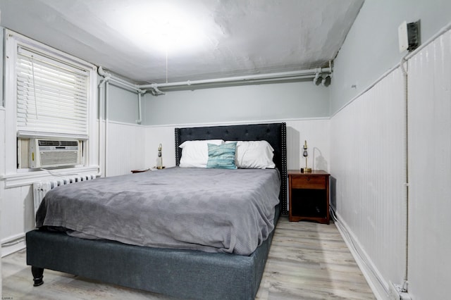 bedroom with light wood-type flooring, cooling unit, and radiator