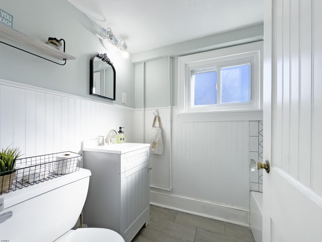 full bath with toilet, vanity, and wainscoting