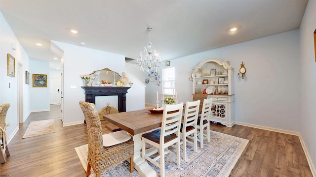 dining room with recessed lighting, baseboards, an inviting chandelier, and wood finished floors