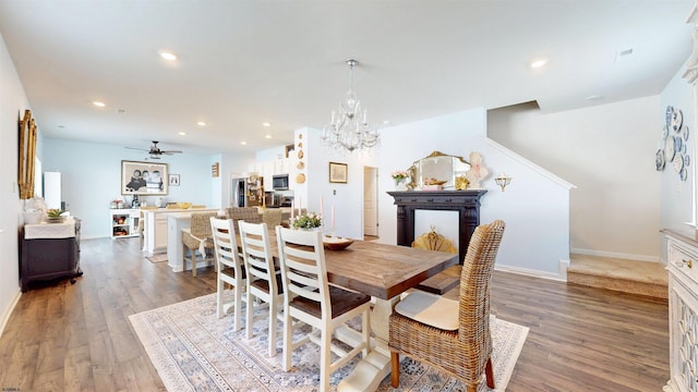 dining space featuring ceiling fan with notable chandelier, baseboards, wood finished floors, and recessed lighting