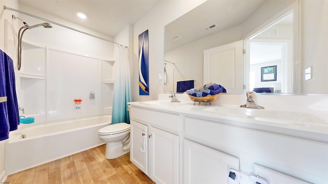 bathroom featuring visible vents, toilet, wood finished floors, shower / bath combination with curtain, and a sink