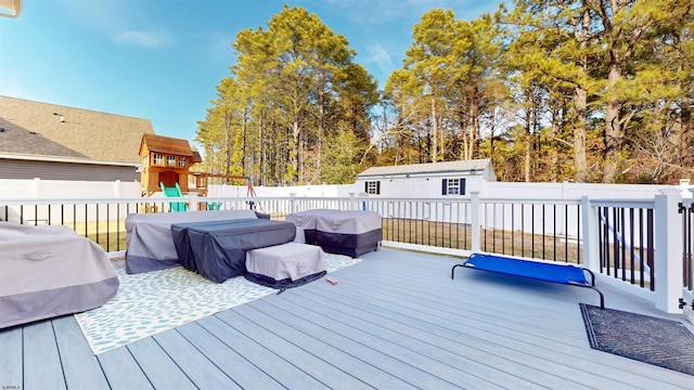 wooden deck with a grill, a fenced backyard, a playground, and an outbuilding