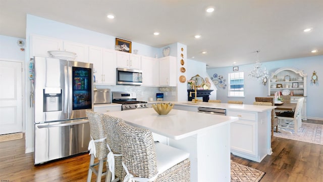 kitchen with stainless steel appliances, light countertops, white cabinetry, a kitchen island, and a peninsula