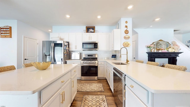 kitchen featuring recessed lighting, appliances with stainless steel finishes, white cabinetry, a sink, and a peninsula