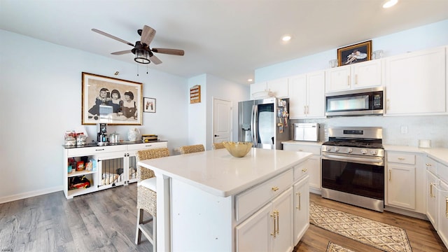 kitchen featuring white cabinets, a kitchen island, stainless steel appliances, and wood finished floors