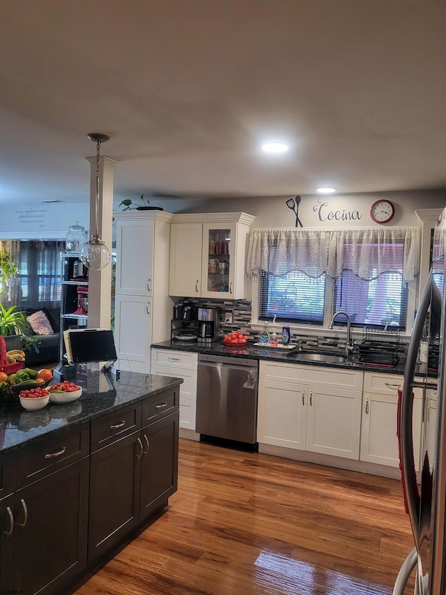 kitchen with dark stone counters, stainless steel dishwasher, glass insert cabinets, and white cabinets