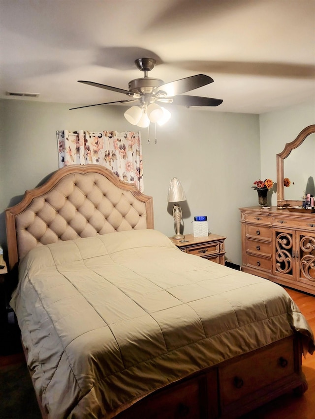 bedroom with a ceiling fan, visible vents, and wood finished floors