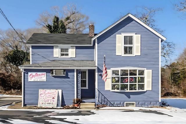 view of front facade with entry steps, a chimney, and a wall mounted AC