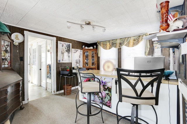 dining area with wood walls and light colored carpet