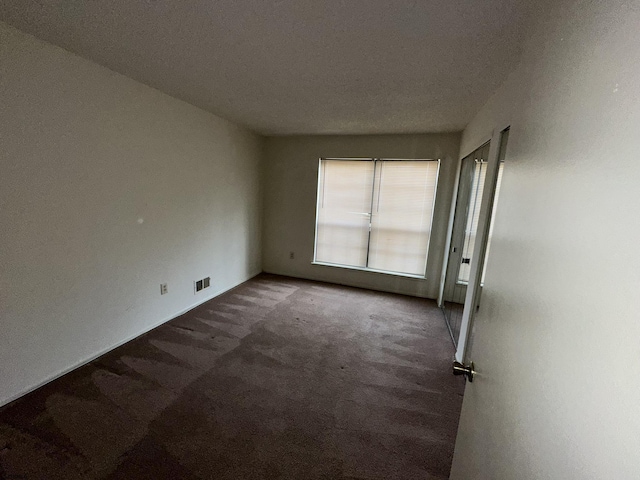 spare room with visible vents and dark carpet