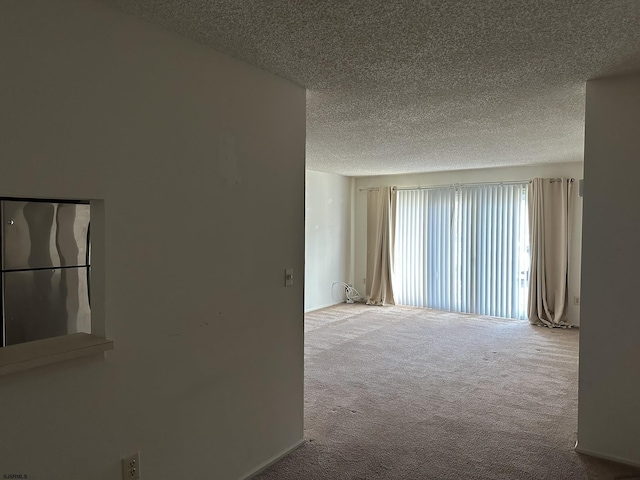 carpeted empty room featuring a textured ceiling