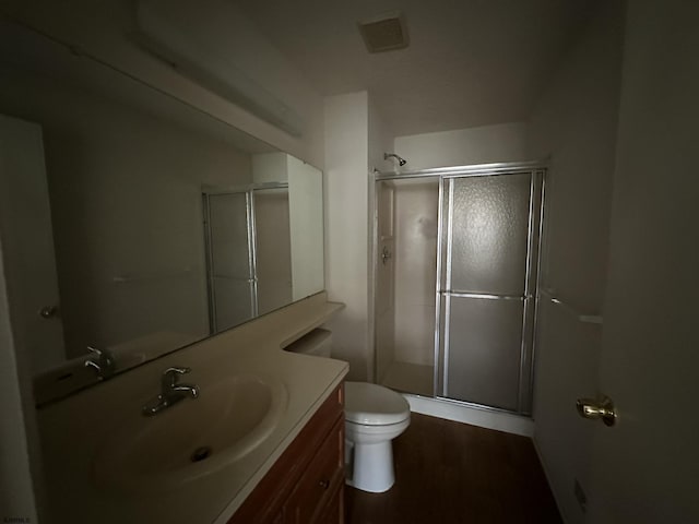 full bath with a stall shower, visible vents, toilet, wood finished floors, and vanity