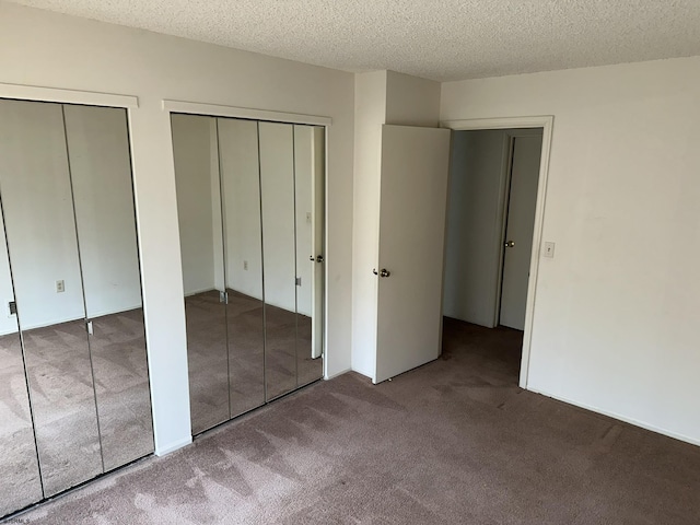 unfurnished bedroom with multiple closets, carpet flooring, and a textured ceiling