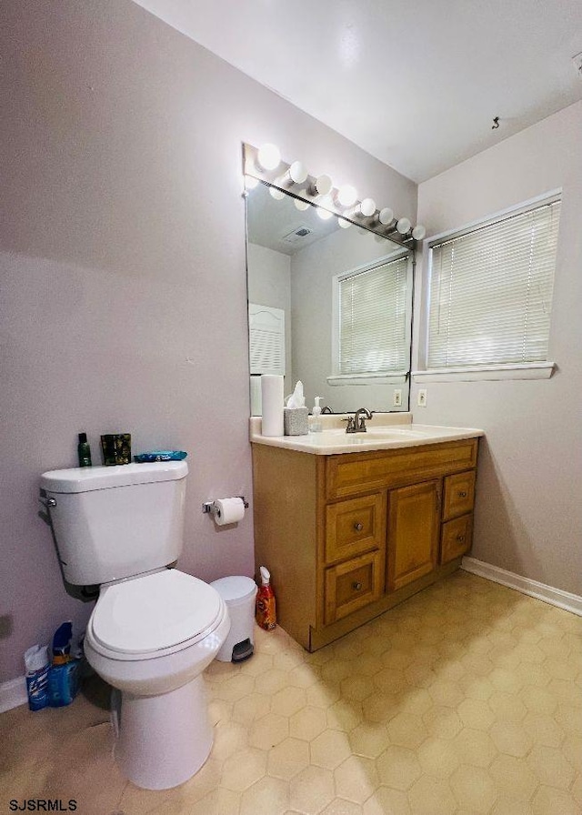 bathroom featuring vanity, toilet, and baseboards