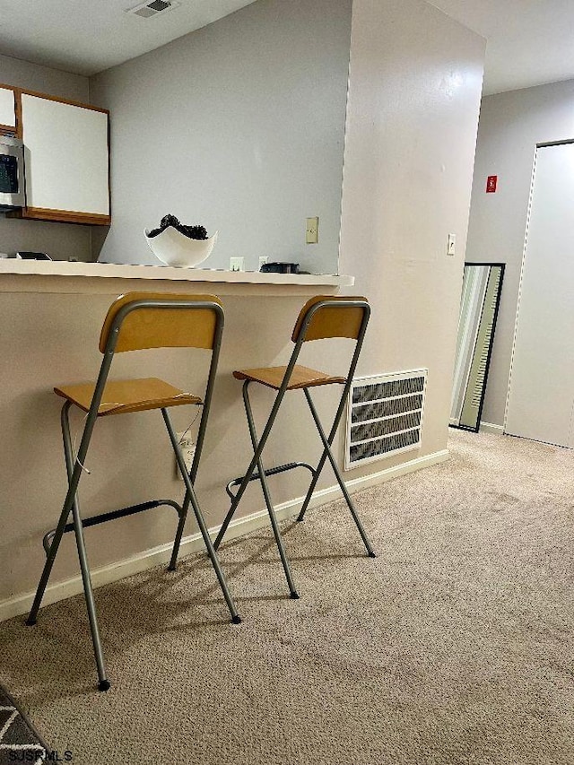 interior space with carpet floors, visible vents, stainless steel microwave, and baseboards