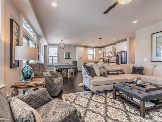 living area with ceiling fan with notable chandelier, dark wood-style flooring, and recessed lighting