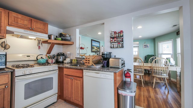 kitchen with visible vents, white appliances, brown cabinets, and under cabinet range hood