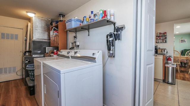 clothes washing area with laundry area, separate washer and dryer, light tile patterned flooring, and visible vents