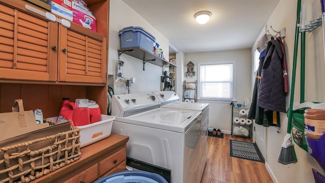 washroom featuring light wood-type flooring, cabinet space, baseboards, and washer and clothes dryer