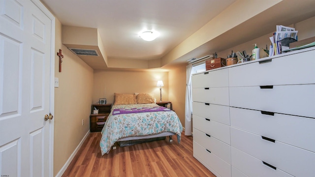 bedroom featuring light wood-style flooring, visible vents, and baseboards