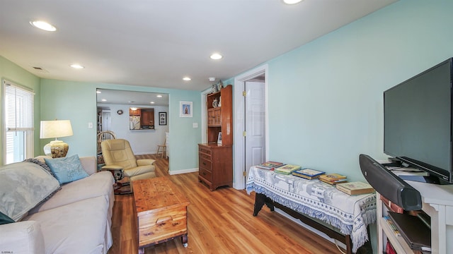 living area featuring baseboards, light wood-type flooring, visible vents, and recessed lighting