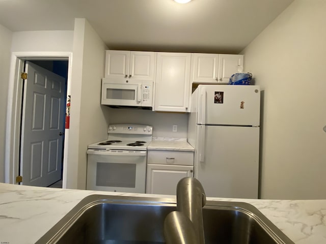 kitchen featuring white appliances, a sink, and white cabinetry