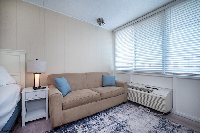 living area featuring a textured ceiling, vaulted ceiling, a wall mounted air conditioner, and wood finished floors