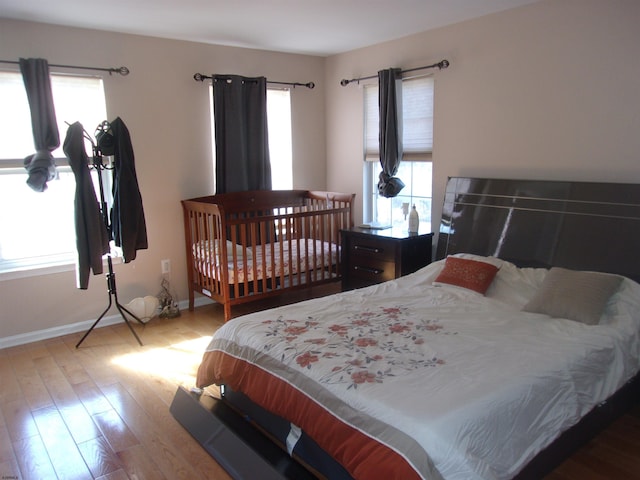 bedroom with multiple windows, wood finished floors, and baseboards