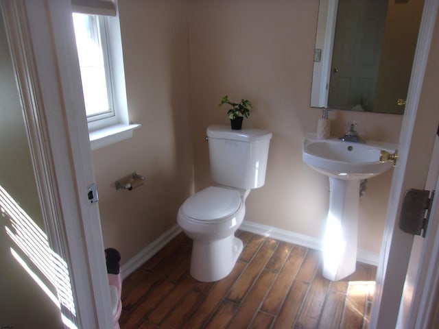 half bath featuring toilet, baseboards, and wood finished floors