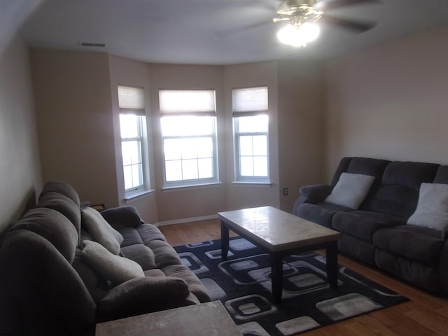 living area featuring ceiling fan, baseboards, and wood finished floors